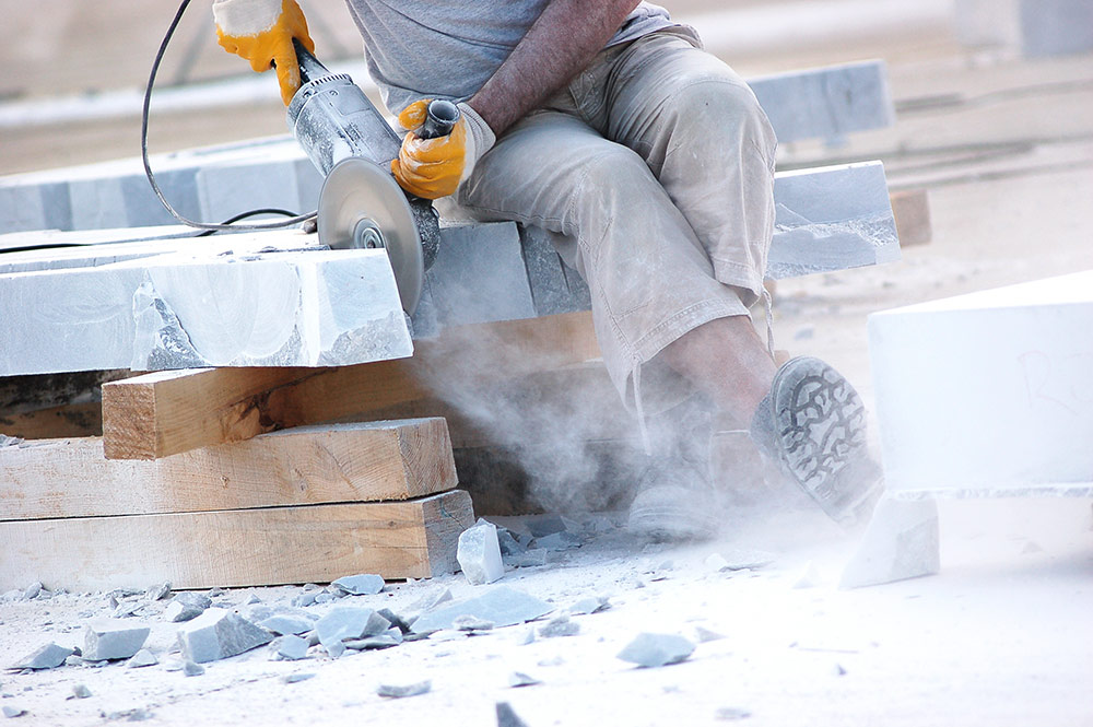 Industrial worker making cut with electric hand saw